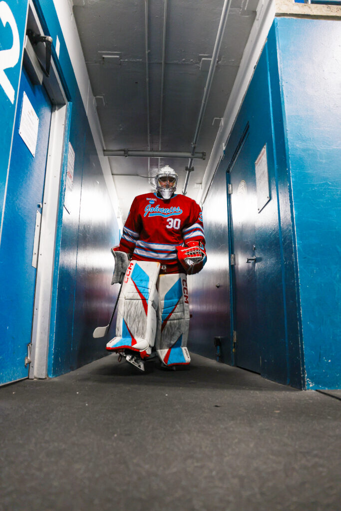 St. John's hockey goalie walking down tunnel in his equipment.